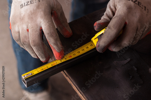 Measurement and welding tool. The worker welds a metal structure.