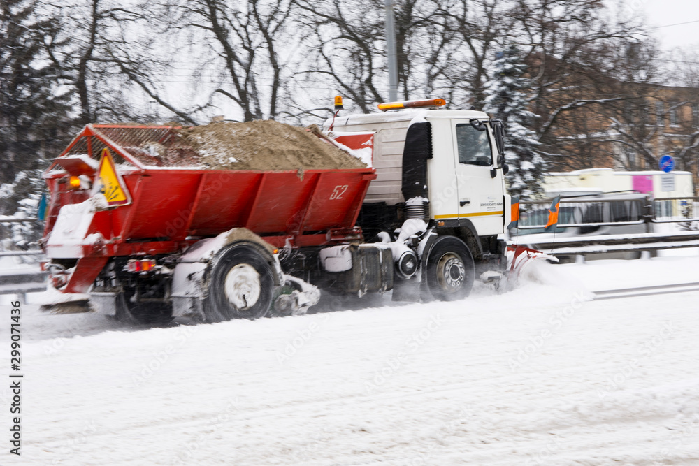 the snow-removing machine works on a snow-covered road. photo a little blurry in motion