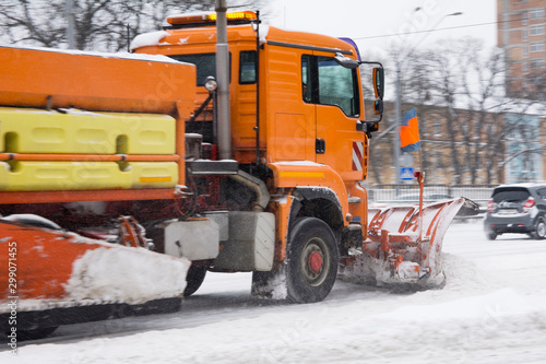 the snow-removing machine works on a snow-covered road. photo a little blurry in motion