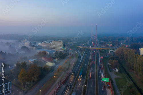 Drone shot of a highway in Warsaw in the morning rush hour, with fog at dusk. Transport. Poland. Aerial view of a freeway with bridges and junctions at sunrise and fog. 