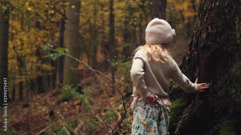 Little girl in hat leans against tree trunk in forest of gold autumn leaves. Little girl in hat leans against tree trunk in forest of gold autumn leaves.