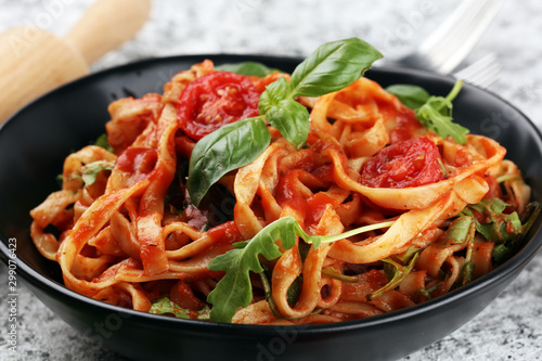 tagliatelle pasta with tomato sauce parmesan basil on rustic background