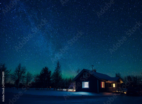 Cottage against the night sky with the Milky Way and the arctic Northern lights Aurora Borealis in snow winter Finland