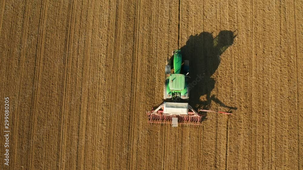 aerial view of haying wheat on field assisted by tractor aerial view of haying wheat on field assisted by tractor