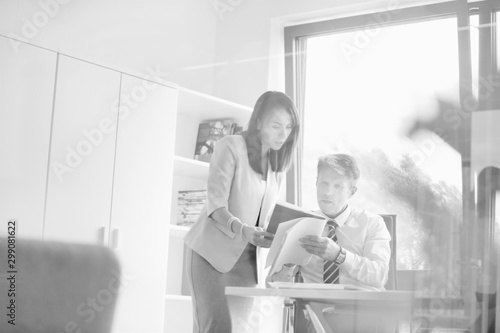 Natural business photographs from a local small business team with real employees wearing formal wear the the office. Attractive female employee is showing senior man a report of numbers in his office