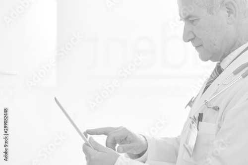 Confident doctor reading medical report on digital tablet at dental clinic