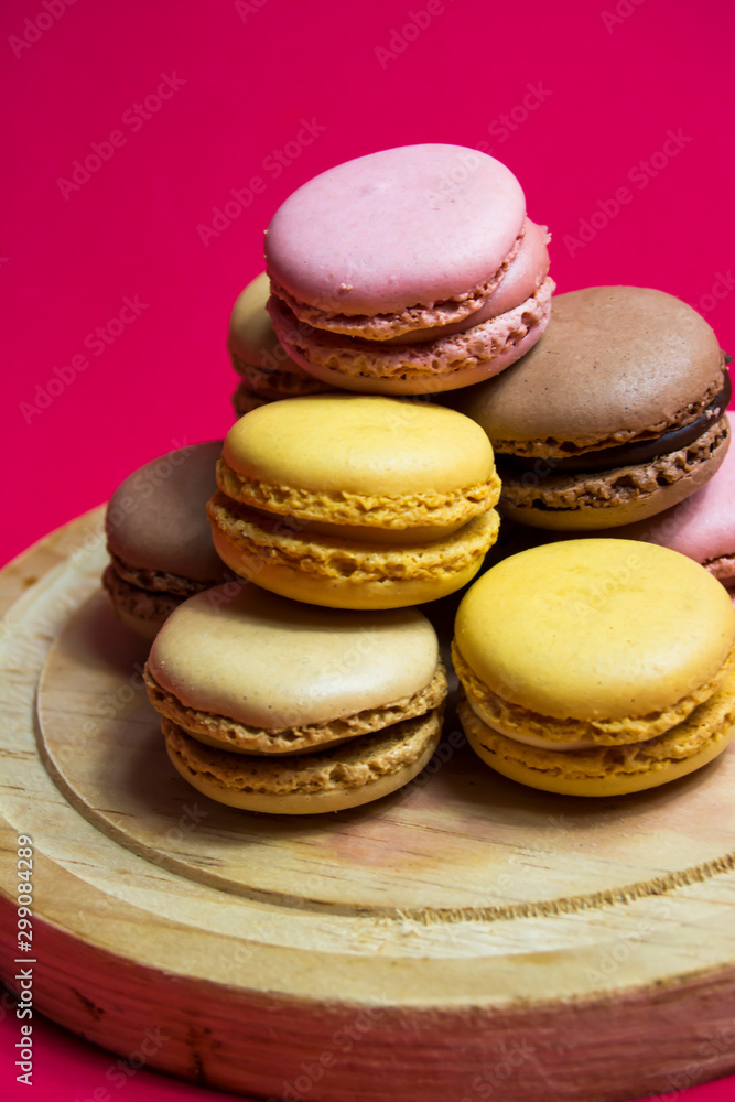 Colored macarons isolated on wooden dish, typical French dish