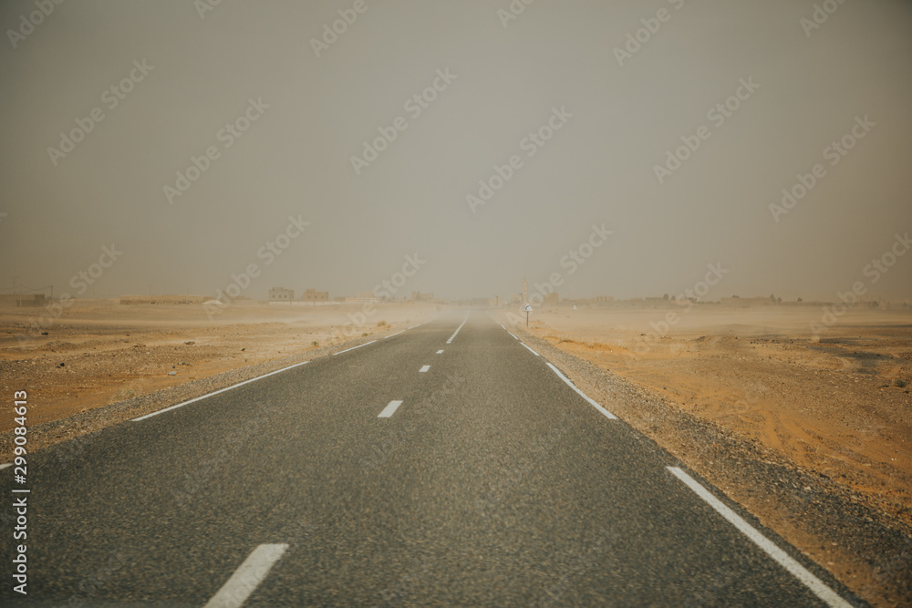 Narrow road crossing africa during sand storm. - obrazy, fototapety, plakaty 
