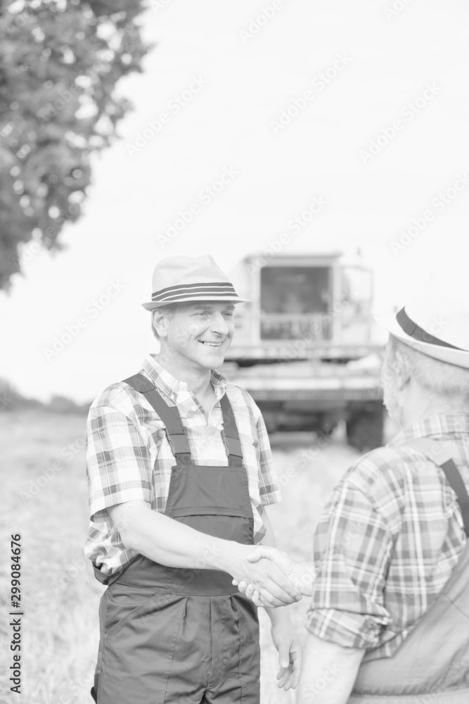 Black and white photo of Mature farmer shaking hands with senior farmer in field