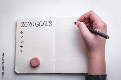 2020 new year goal plan action text on notepad with woman s hands.