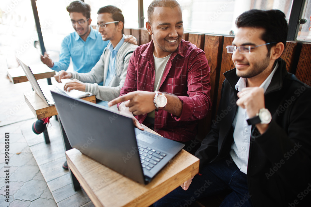 Fototapeta premium Group of four indian teen male students. Classmates spend time together and work at laptops.