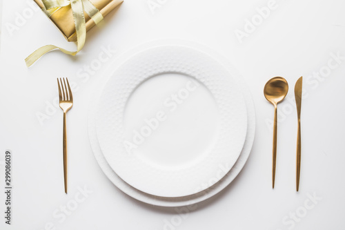 Elegant table setting with golden cutlery on white background. Top view.