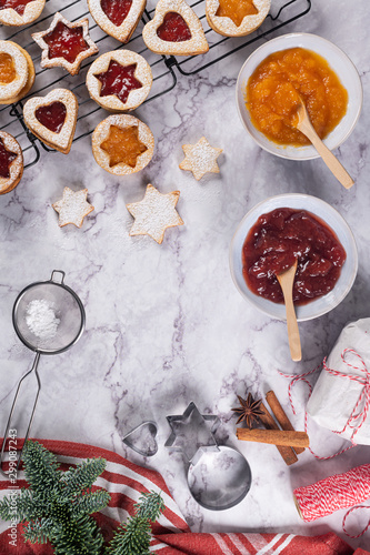Flat lay with christmas cookies on marble surface with christmas decorative pine branch  jam  gift and cookie cutters