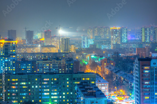 Top view of the city. Colorful street lighting of the night metropolis. Many high-rise buildings. Cold winter weather. Light haze. Novosibirsk, Siberia, Russia.