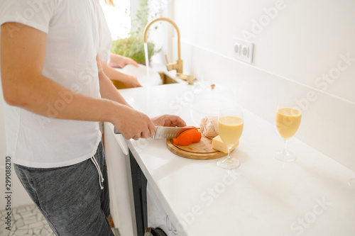  A man cuts tomatoes on a cutting board in a bright kitchen