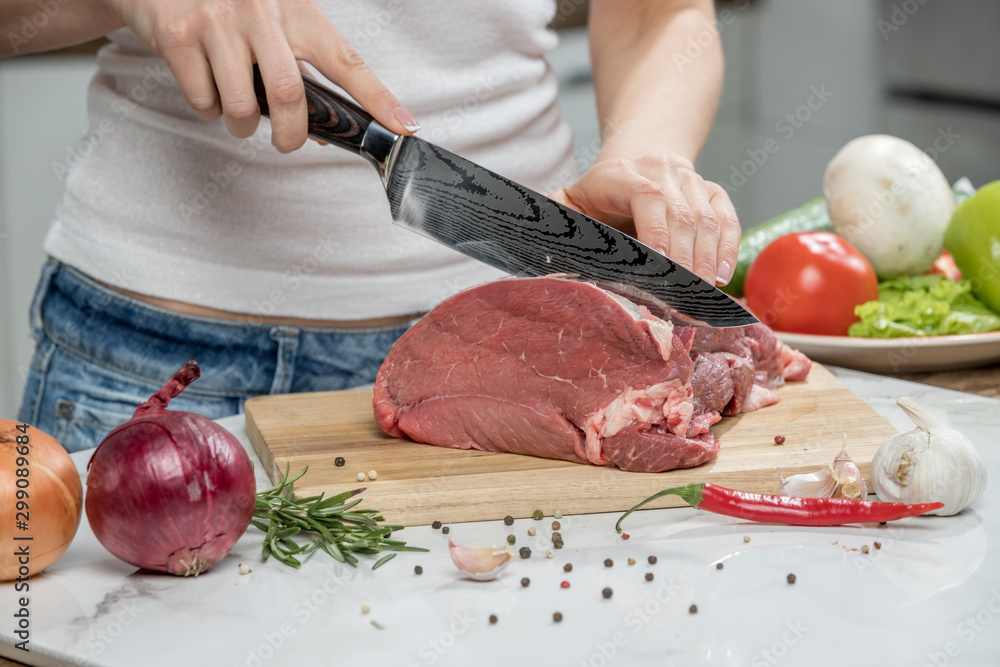 Close up of woman's hands cooking in the kitchen. Housewife slicing fresh meat.