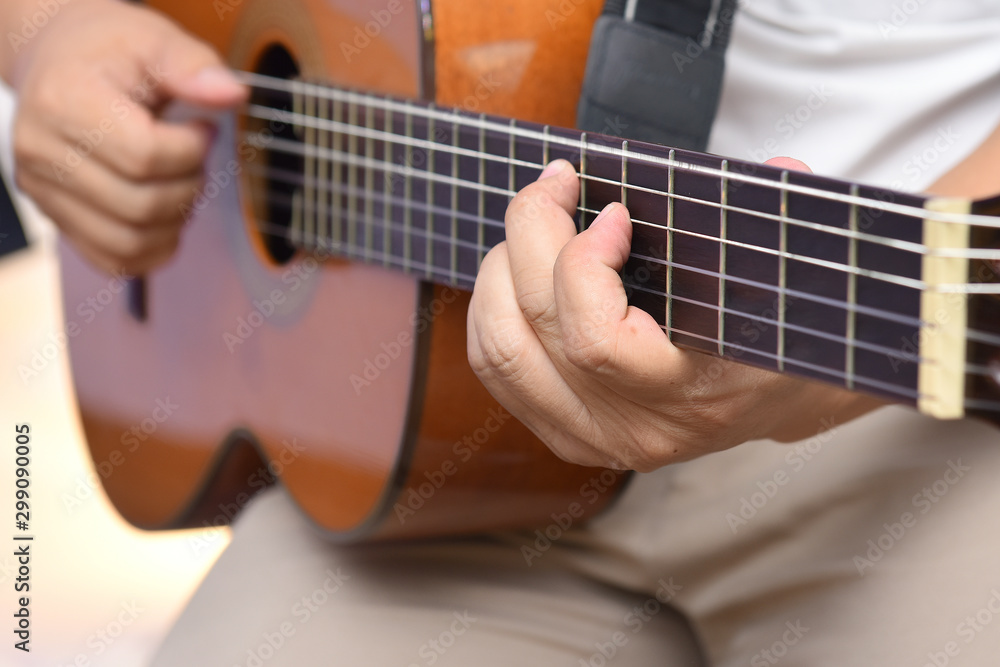 Hands of the guitarist, playing a melody on a wooden six-string acoustic guitar