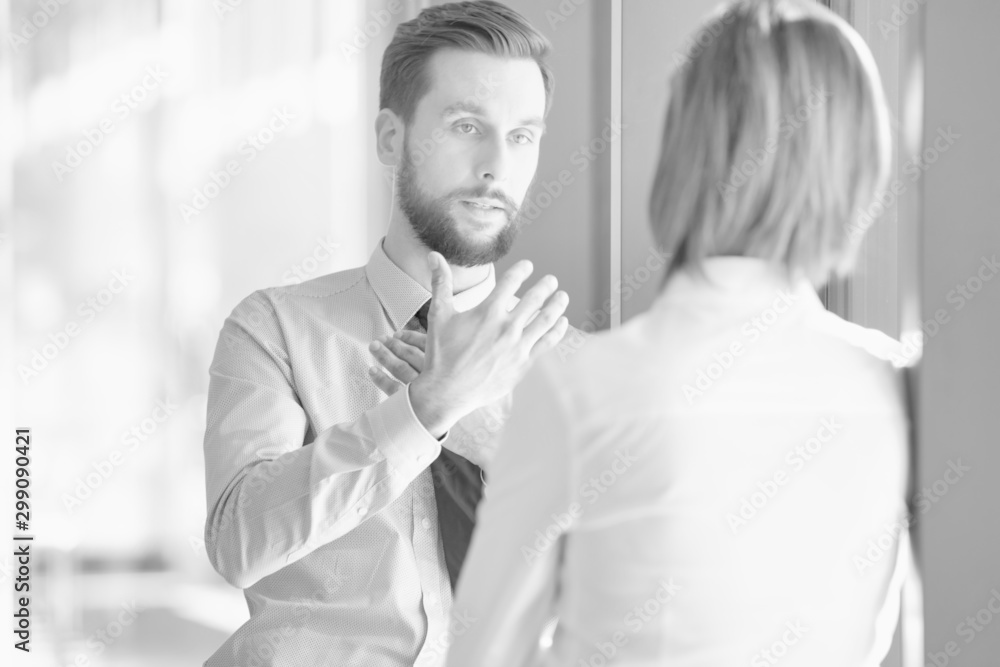 Fototapeta premium Black and white photo of businessman discussing plans with businesswoman before meeting