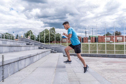 Athletic man running, jogging stairs, training in city during summer, an active lifestyle, modern fitness workout. Free space for motivation text.