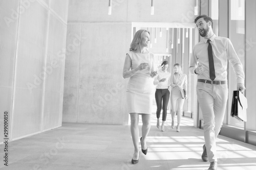 Black and white photo of business people discussing plans before meeting while walking in office hall