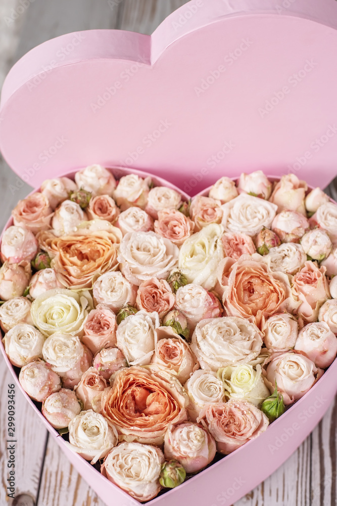 A box in the shape of a heart with tiny buds of delicate roses on a rough wooden background. Vinage.
