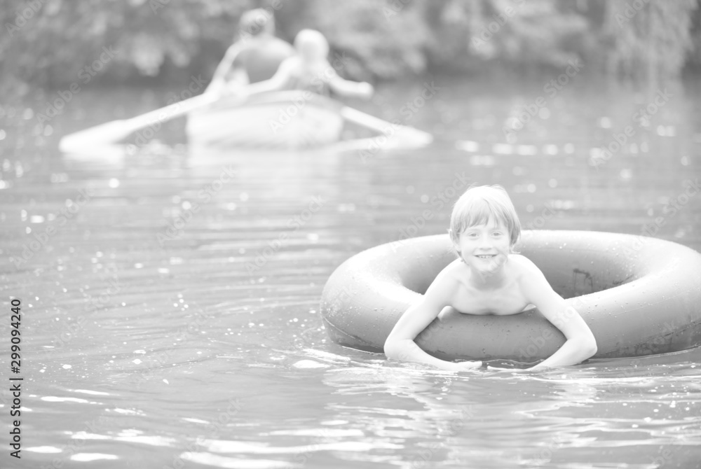 Portrait of smiling boy floating with inflatable ring in lake against family
