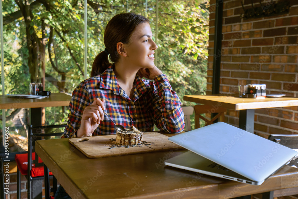 Attractive happy young woman sitting and eating dessert in cafe Attractive happy young woman sitting and eating dessert in cafe