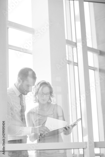Businesswoman discussing with businessman over document at office