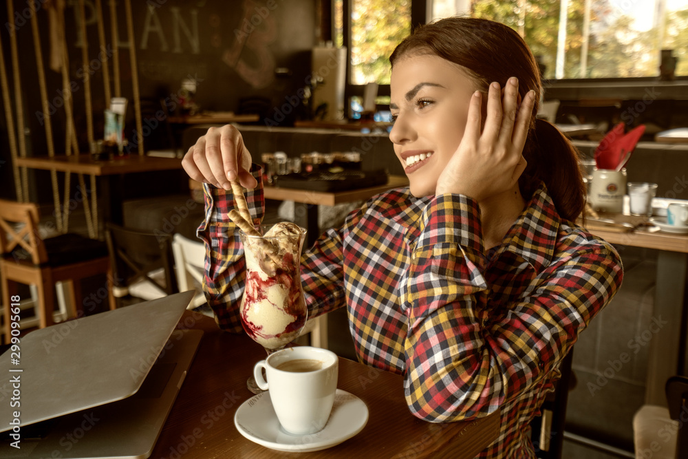 Attractive happy young woman sitting and eating dessert in cafe Attractive happy young woman sitting and eating dessert in cafe
