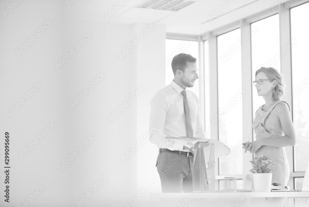 Fototapeta premium Businessman and businesswoman discussing at desk in new office