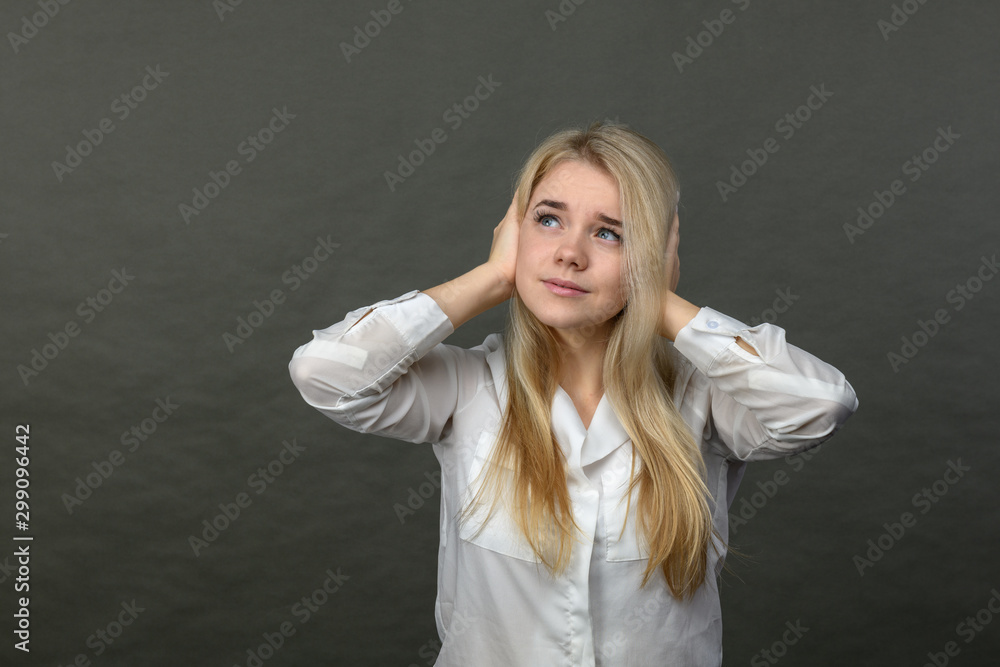 Young beautiful blonde woman with stress and headaches on a gray background. Woman holding her head. Pretty woman with a headache.
