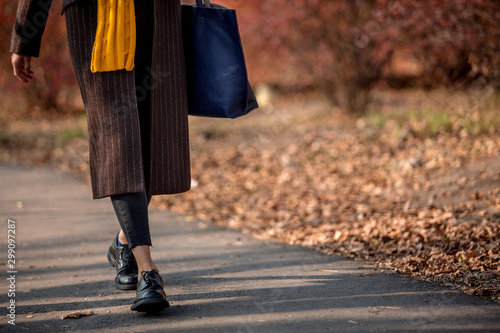 Closeup legs fashionable woman wear black shoes and brown coat. Stylish fall outfit