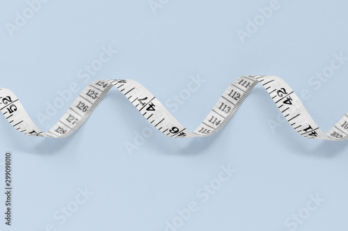 White measuring tape isolated on a blue background, with copy space photo