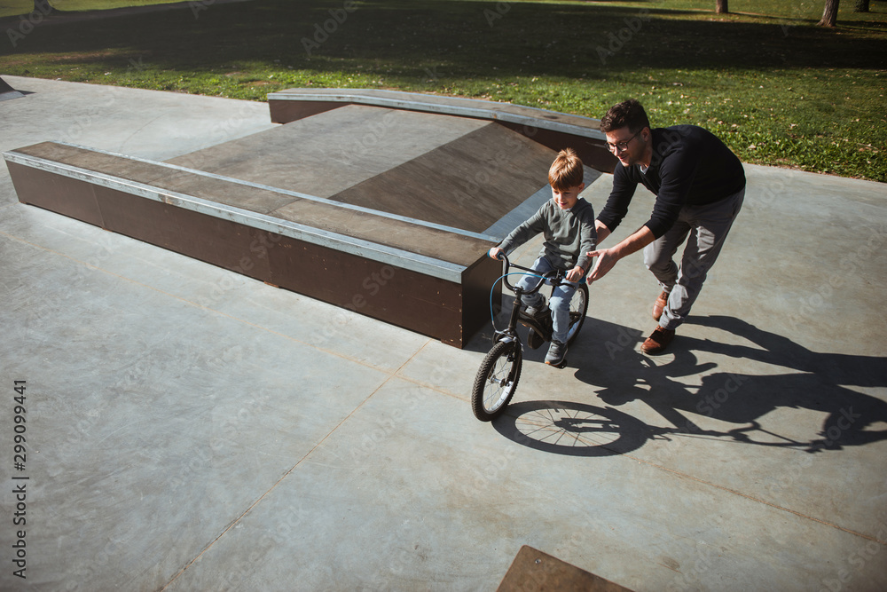 Obraz premium Father Learning his son to ride a bicycle