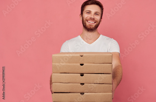 Courier holds many pizza boxes isolated on wall