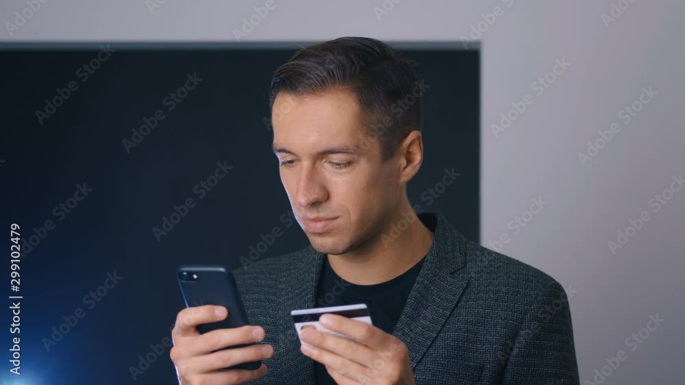 Young business man shopping online with credit card using smartphone at office. Online banking mobile app. Young business man shopping online with credit card using smartphone at office. Online banking mobile app.