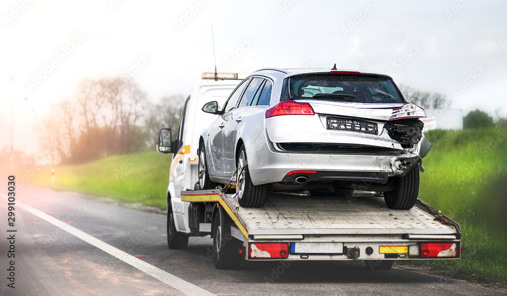 Loading broken car on a tow truck. Damage vehicle after crash accident on the highway road.