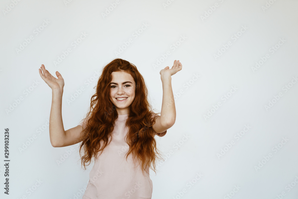 Cute schoolgirl smiling looking at the camera and raised her hands up. light background Cute schoolgirl smiling looking at the camera and raised her hands up. light background