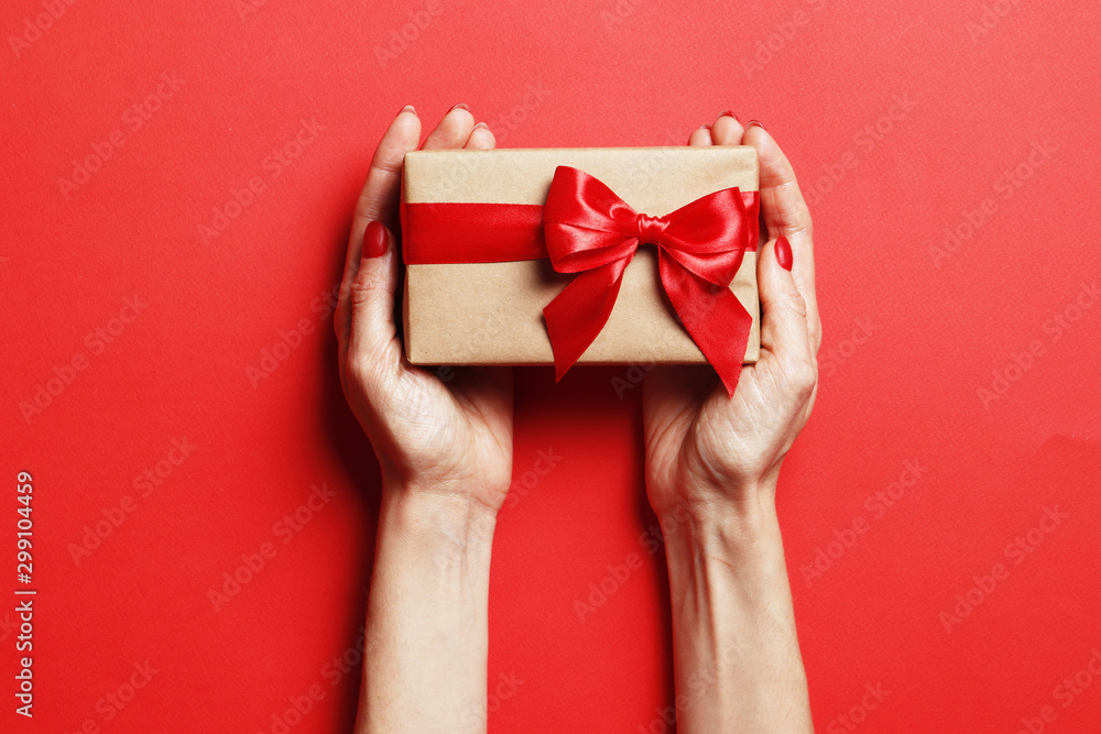 Christmas gift box in a female hand on a red background. Place for text. Christmas gift box in a female hand on a red background. Place for text.