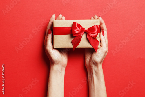 Fototapeta Naklejka Na Ścianę i Meble -  Christmas gift box in a female hand on a red background. Place for text.