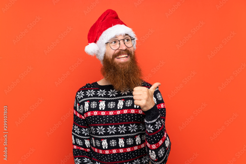 Christmas man with long beard over isolated red background pointing to the side to present a product Christmas man with long beard over isolated red background pointing to the side to present a product