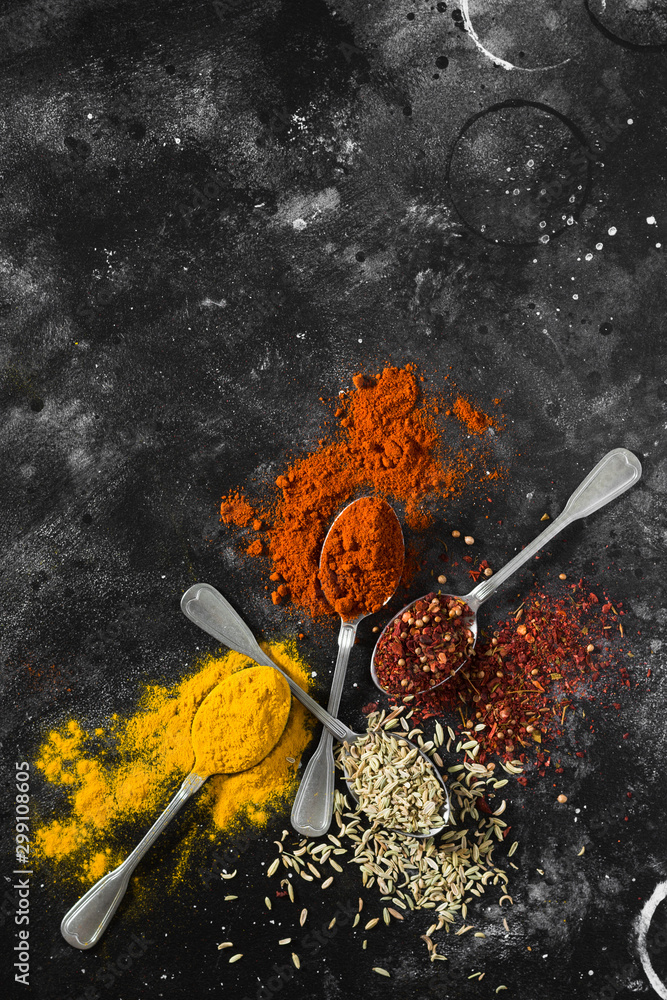 Spices in metal spoons on a black table Spices in metal spoons on a black table