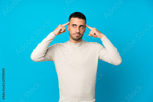Young man over isolated blue background having doubts and thinking