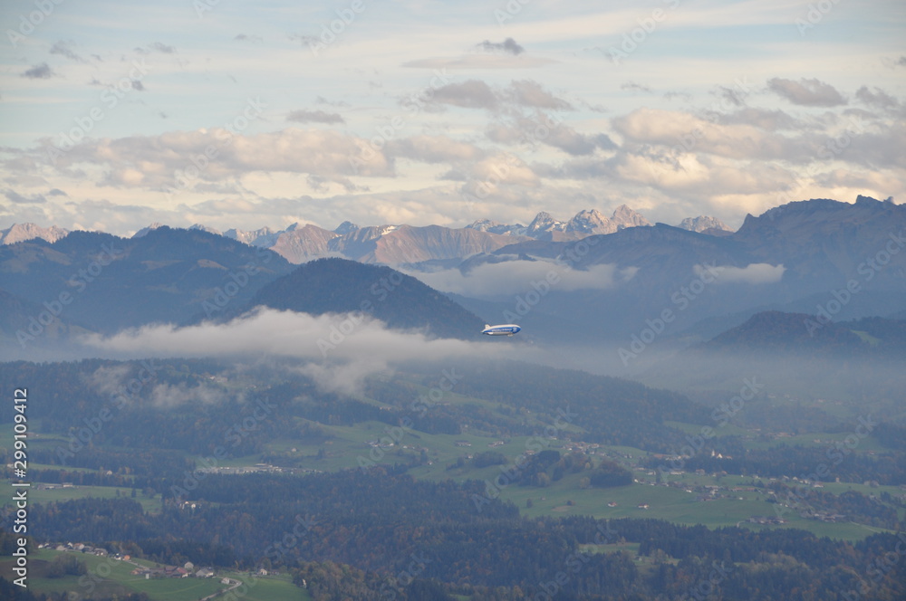 a zeppelin airship flying over the Alps seen from the Pfänder, Voralberg, Austria