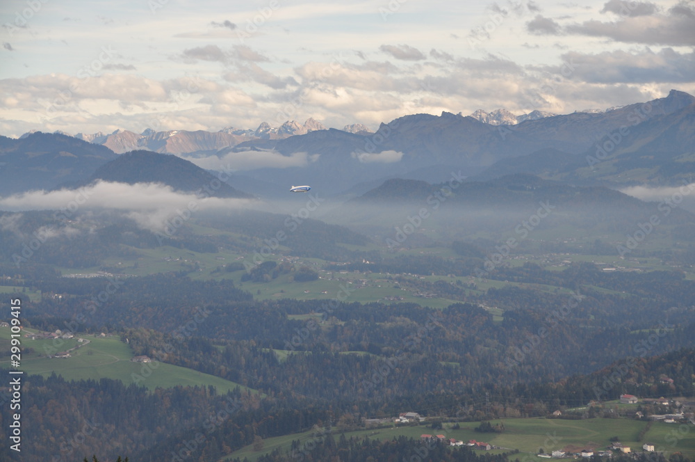 a zeppelin airship flying over the Alps seen from the Pfänder, Voralberg, Austria