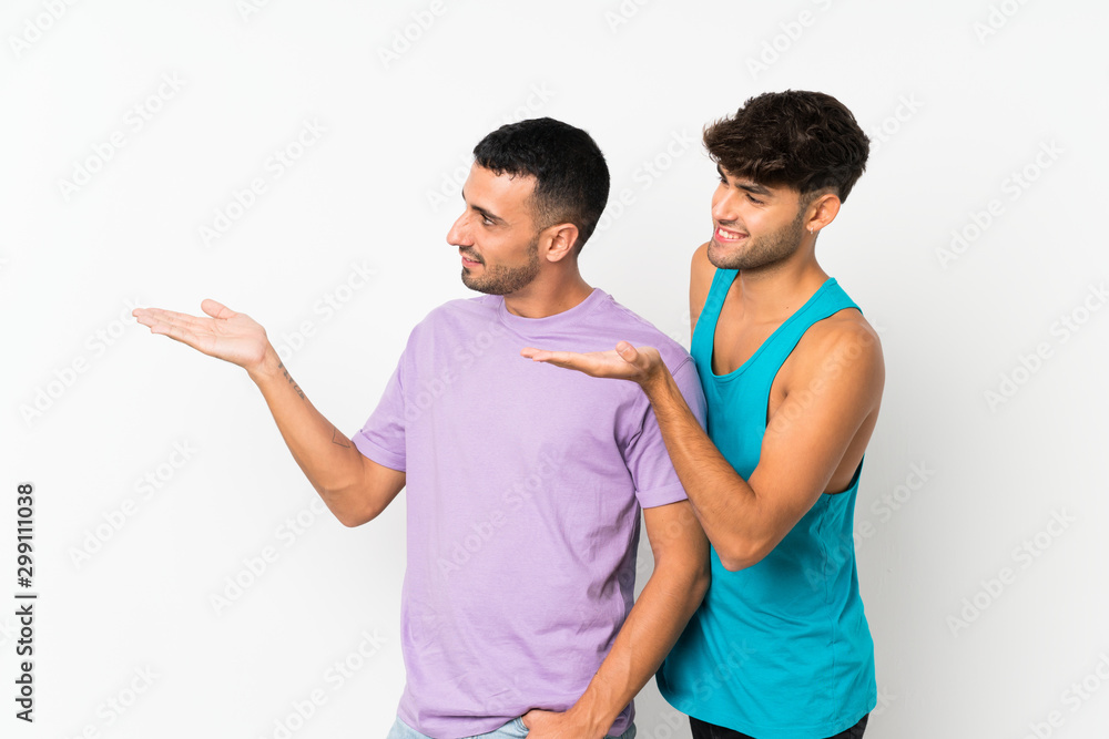 Fototapeta premium Two men over isolated background pointing back and presenting a product