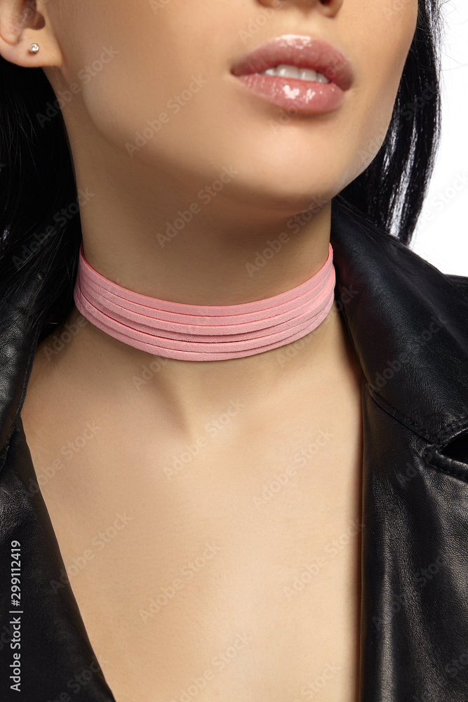 Cropped extreme close-up shot of a black-haired lady in a black leather  jacket and with a pink multi-layered choker consists of thin suede stripes.  Stock Photo | Adobe Stock