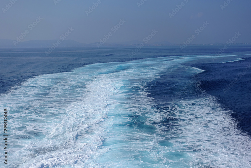 Obraz premium Large white waves generated from high speed boat in deep blue Aegean sea and sky