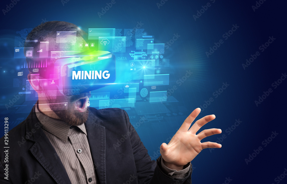 Businessman looking through Virtual Reality glasses with MINING inscription, innovative security concept Businessman looking through Virtual Reality glasses with MINING inscription, innovative security concept