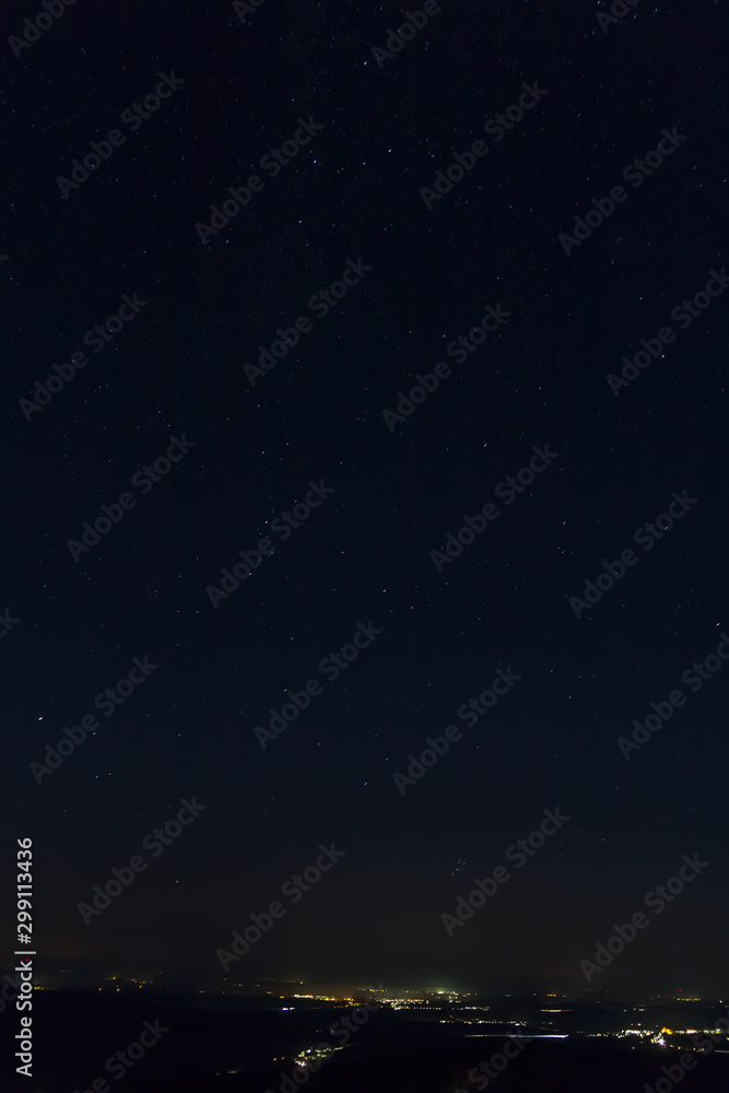 Night sky full of stars with distant city, long exposure, Austria landscape
